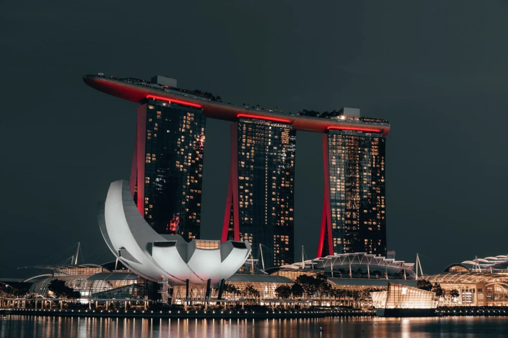Dramatic night view of Marina Bay Sands, Singapore, with glowing cityscape and reflection.